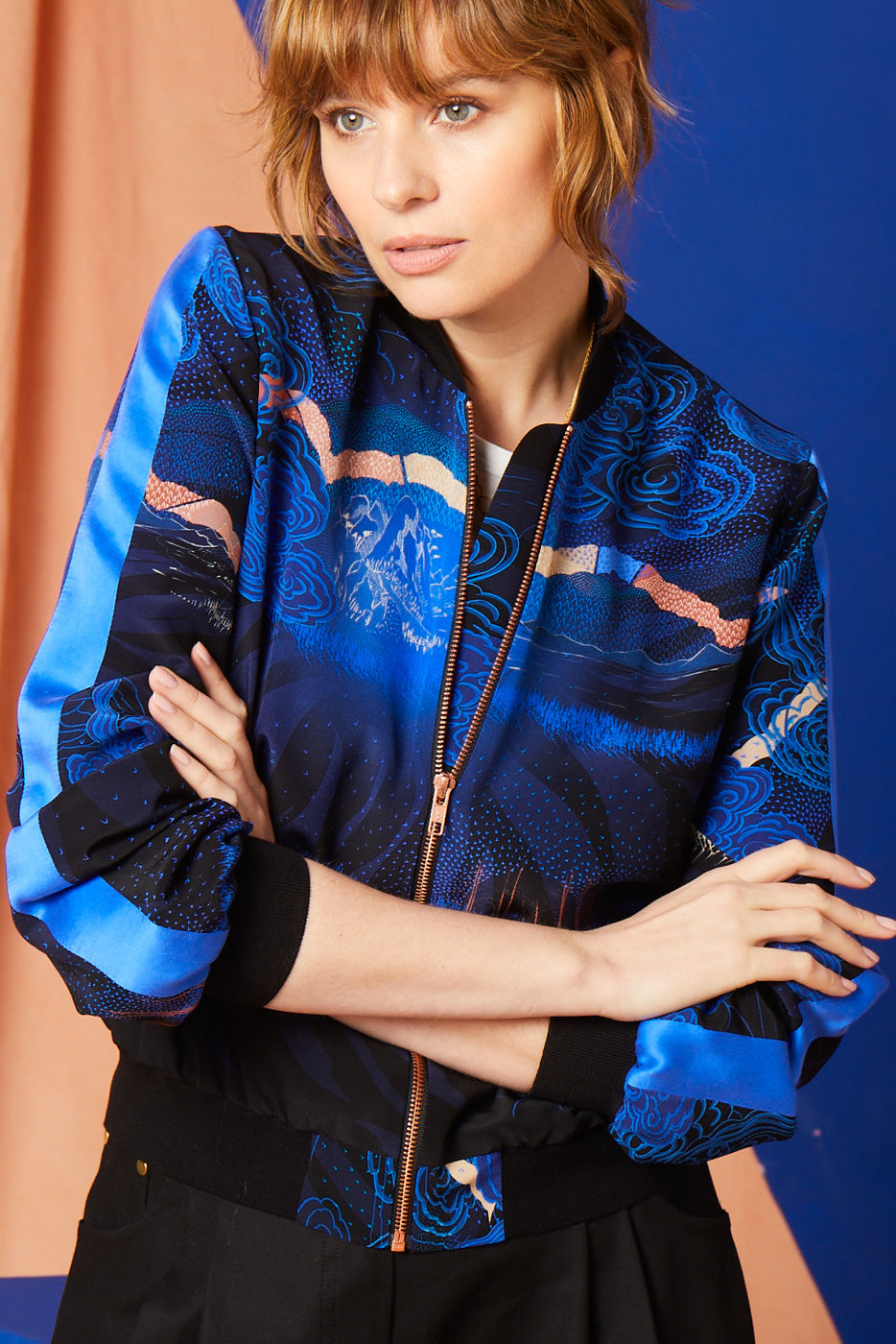 A women wearing a Silk Bomber jacket with Japanese landscapes in blues and pinks